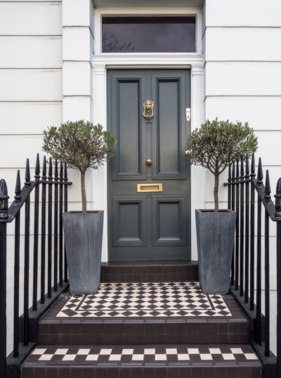 elegant entrance with olive trees and geometric floor tiles showcasing four stylish planters and a classic door